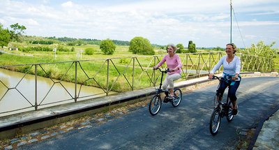 Deux femmes à vélo sur un pont sur le Canal du Midi